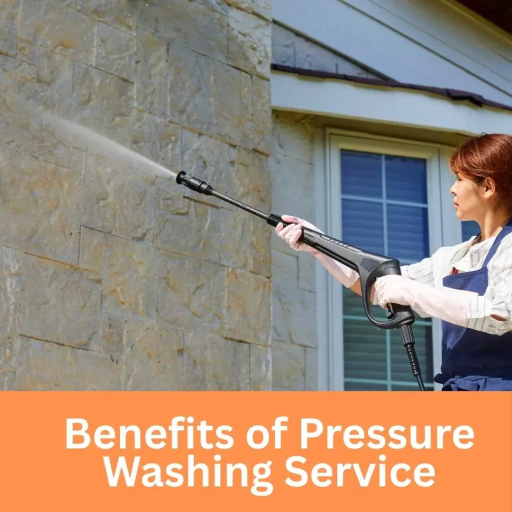 Person using a pressure washer to clean the exterior wall of a house on a bright, clear day.