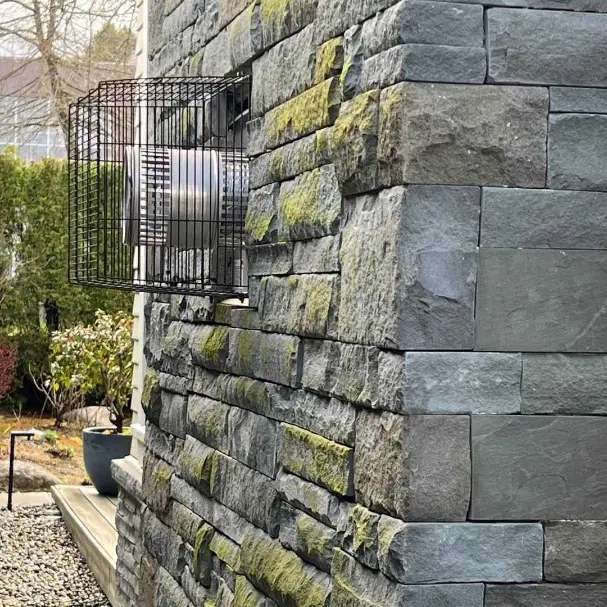 Stone wall with a large industrial fan unit installed outside, used for ventilation or cooling in commercial buildings.