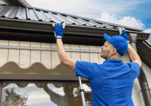 Worker installs metal roof with blue gloves.