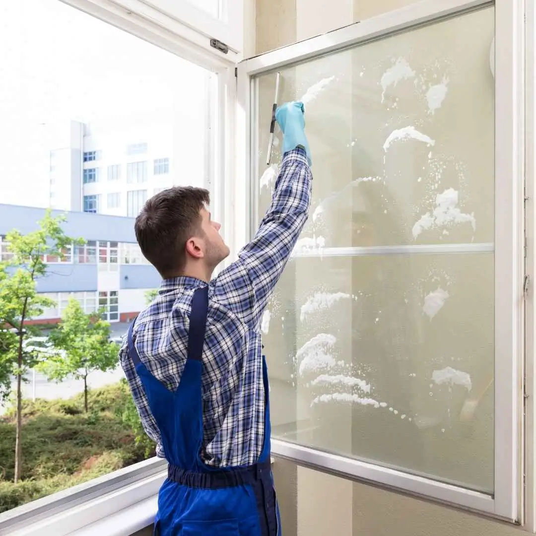 Person cleaning window with squeegee indoors